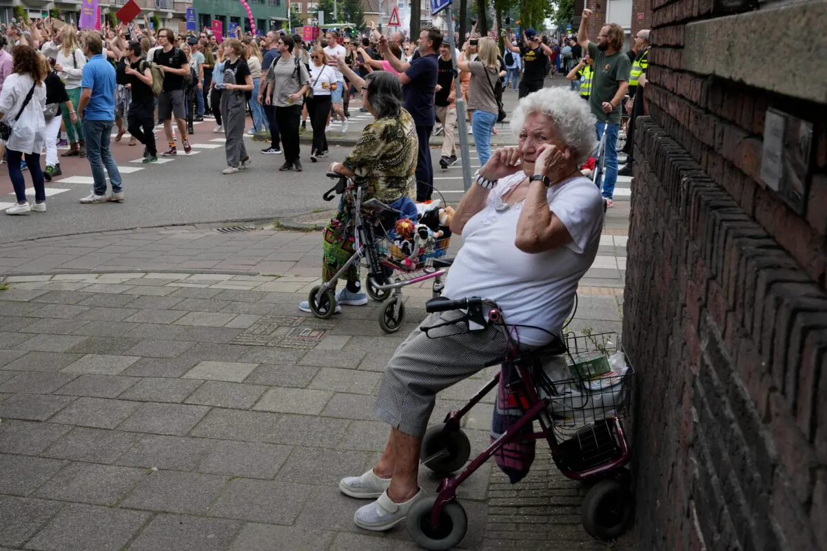 An older woman shields her ears during a protest of organizers and fans of music festivals stage against the government's COVID-19 restrictions on large-scale outdoor events, in Amsterdam, Netherlands, on Aug. 21, 2021. (Peter Dejong /AP Photo)