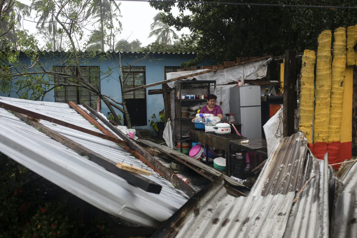 A woman begins clearing debris from her kitchen after a part of her home was damaged by winds brought on by Hurricane Grace, in Tecolutla, Veracruz State, Mexico, on Aug. 21, 2021. (Felix Marquez/AP Photo)