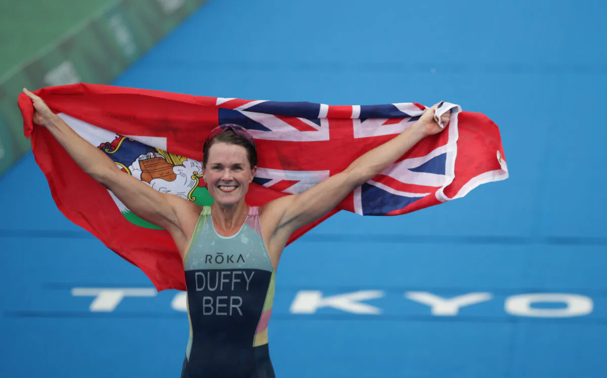 Flora Duffy of Bermuda holds the national flag as she celebrates victory during the women's individual triathlon competition at the Tokyo 2020 Olympic Games at the Odaiba Marine Park in Tokyo, Japan, on July 27, 2021. (Hannah Mckay/Reuters)
