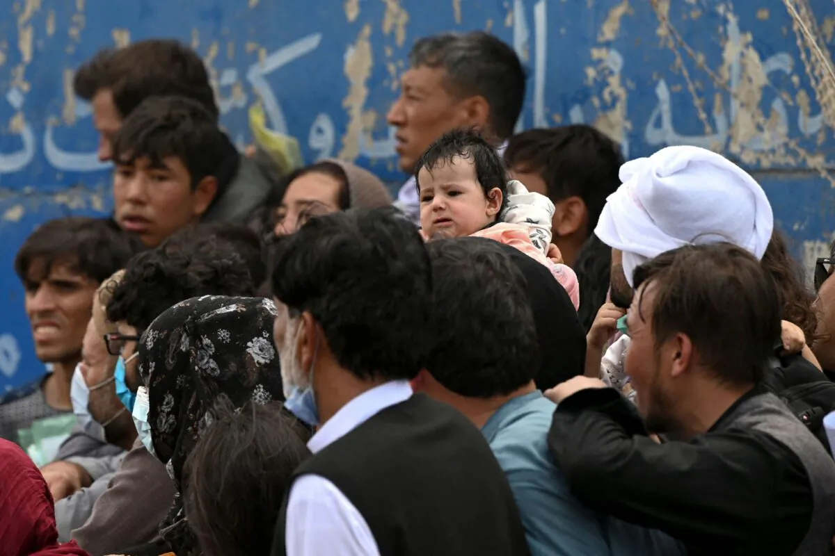 Afghans gather on a roadside near the military part of the airport in Kabul, on Aug. 20, 2021. (Wakil Kohsar/AFP via Getty Images)