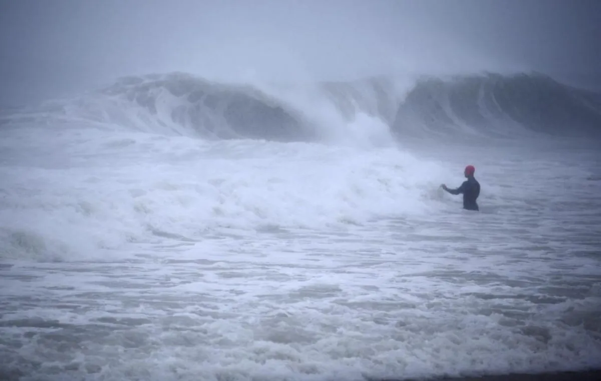 Matt Prue, from Stonington, Conn., walks out into the Atlantic Ocean to body surf the waves from Tropical Storm Henri as it approaches Westerly, R.I., on Aug. 22, 2021. (Stew Milne/AP Photo)