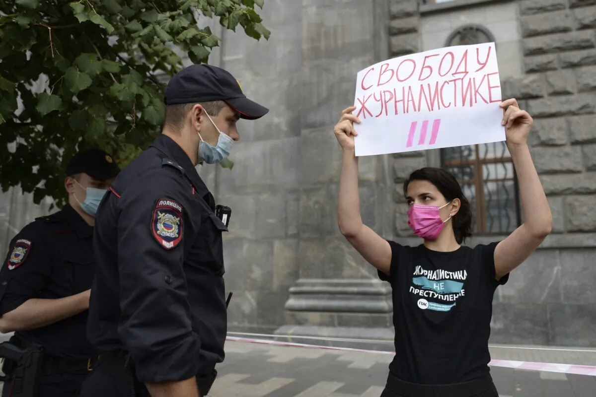 Police detain a journalist with a poster reading "Journalism Freedom" during individual pickets in Moscow on Aug. 21, 2021. (Denis Kaminev/AP Photo)