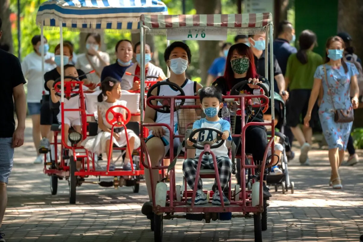 Adults and children ride pedal cycles at a public park in Beijing on Aug. 21, 2021. China will now allow couples to have a third child as the country seeks to hold off a demographic crisis that threatens its hopes of increased prosperity and global influence. (AP Photo/Mark Schiefelbein)