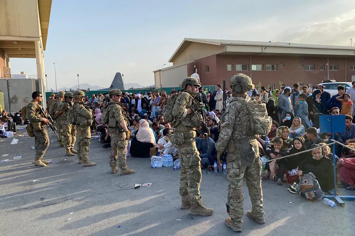 U.S. soldiers stand guard as Afghan people wait to board a U.S. military aircraft to leave Afghanistan, at the military airport in Kabul on Aug. 19, 2021. (Shakib Rahmani/AFP via Getty Images)