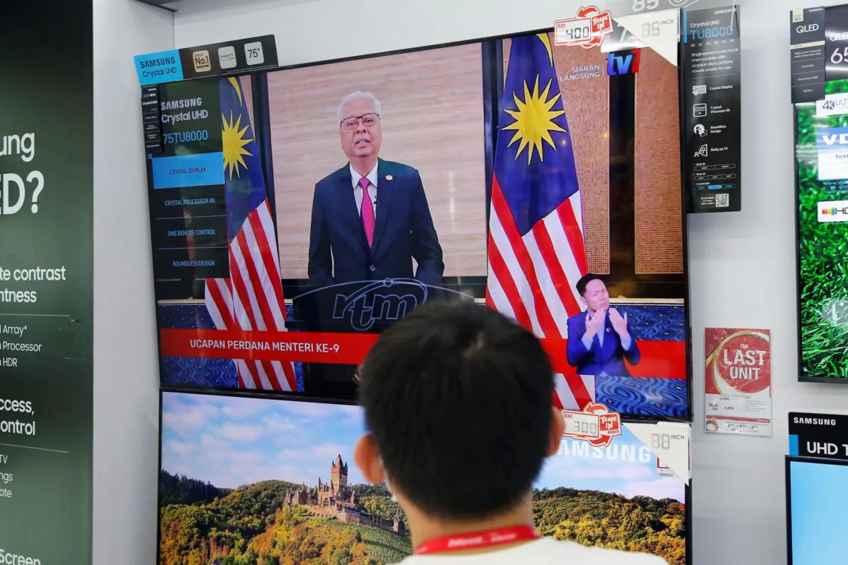 An electronic shop worker watches a speech by Malaysia's new Prime Minister Ismail Sabri Yaakob on television in Shah Alam, Malaysia, Aug. 22, 2021. (Lai Seng Sin/AP Photo)