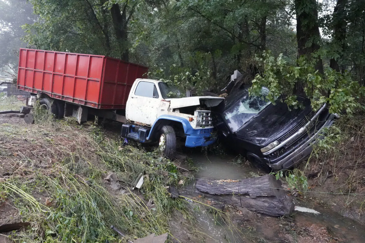 A truck and a car sit in a creek after they were washed away the day before in McEwen, Tenn., on Aug. 22, 2021. (Mark Humphrey/AP Photo)