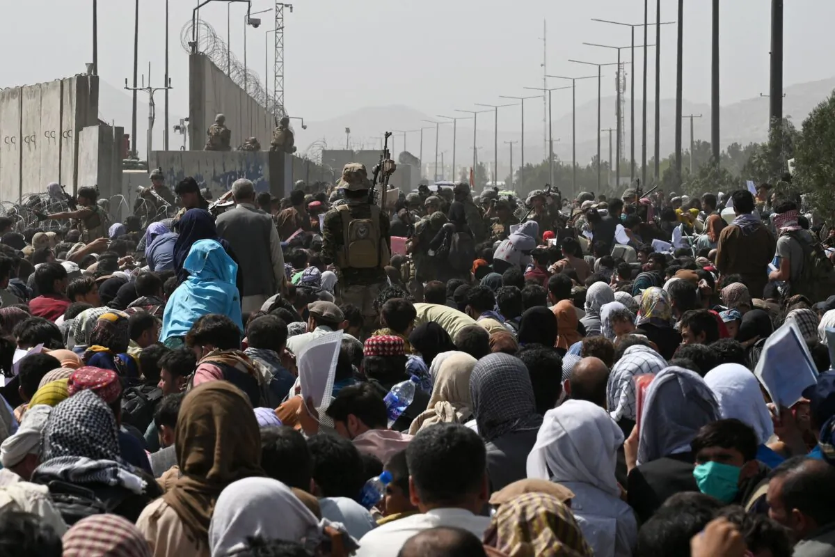 Afghans gather on a roadside near the military part of the airport in Kabul hoping to flee from the country after the Taliban's military takeover of Afghanistan on Aug. 20, 2021. (Wakil Kohsar/AFP via Getty Images)