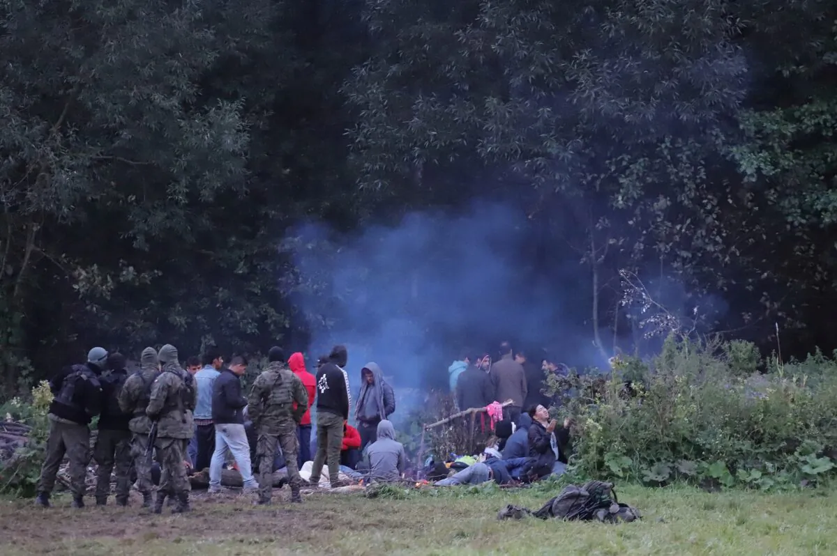Polish border patrol officers guard a group of illegal immigrants who attempted to cross the border between Belarus and Poland near the village of Usnarz Gorny, Poland, on Aug. 18, 2021. (Grzegorz Dabrowski/Agencja Gazeta/via Reuters)