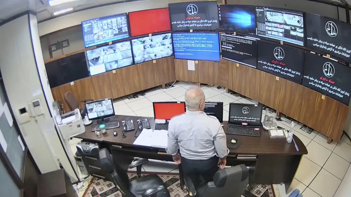 In this undated frame grab taken from video shared with The Associated Press by a self-identified hacker group called "The Justice of Ali," a guard looks at surveillance screens taken over by the group, at Evin prison in Tehran, Iran. (The Justice of Ali via AP)