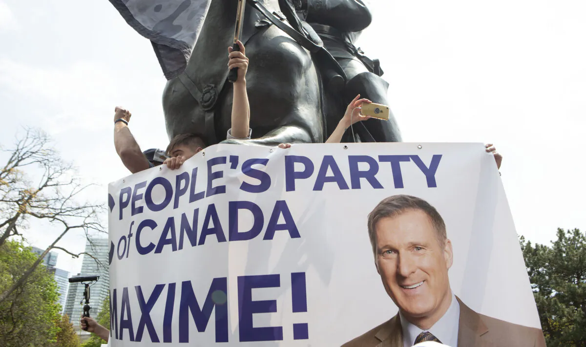 Supporters of Maxime Bernier, Leader of the People's Party of Canada hold up a banner as he speaks to the crowd as protesters demonstrate against measures taken by government and public health authorities to curb the spread of COVID-19, in Toronto, May 15, 2021. (The Canadian Press/Chris Young)