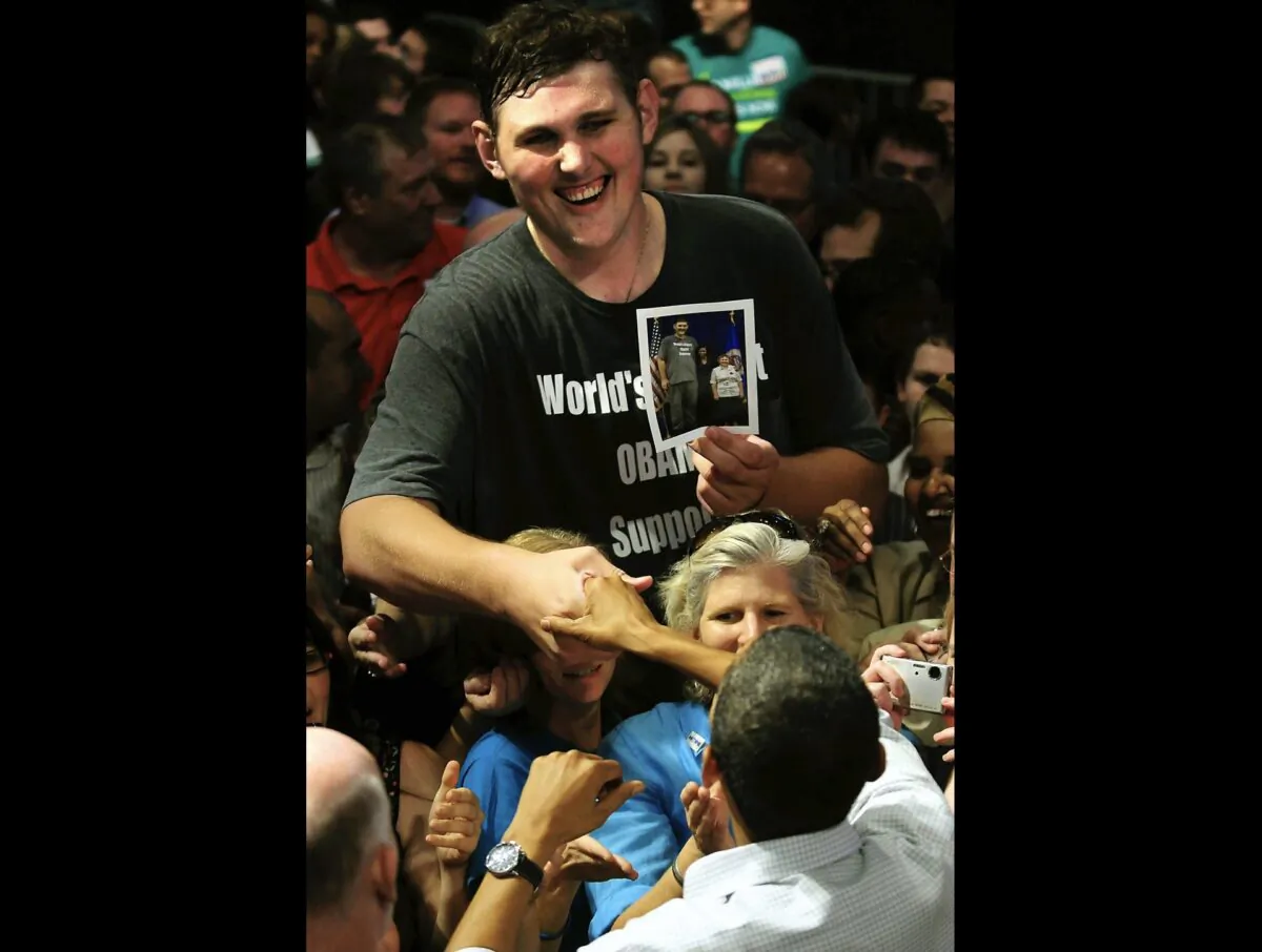 President Barack Obama, foreground, reaches up to shake the hand of 7 feet 8 inch tall Igor Vovkovinskiy, then 27, of Rochester, Minn. during a health care reform rally at the Target Center in Minneapolis, Minn., on Sept. 12, 2009. (Ben Garvin/St. Paul Pioneer Press via AP)