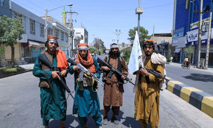 Taliban fighters stand guard along a road near the site of an Ashura procession which is held to mark the death of Imam Hussein, the grandson of Prophet Mohammad, along a road in Herat on Aug. 19, 2021, amid the Taliban's military takeover of Afghanistan. (Aref Karimi/AFP via Getty Images)