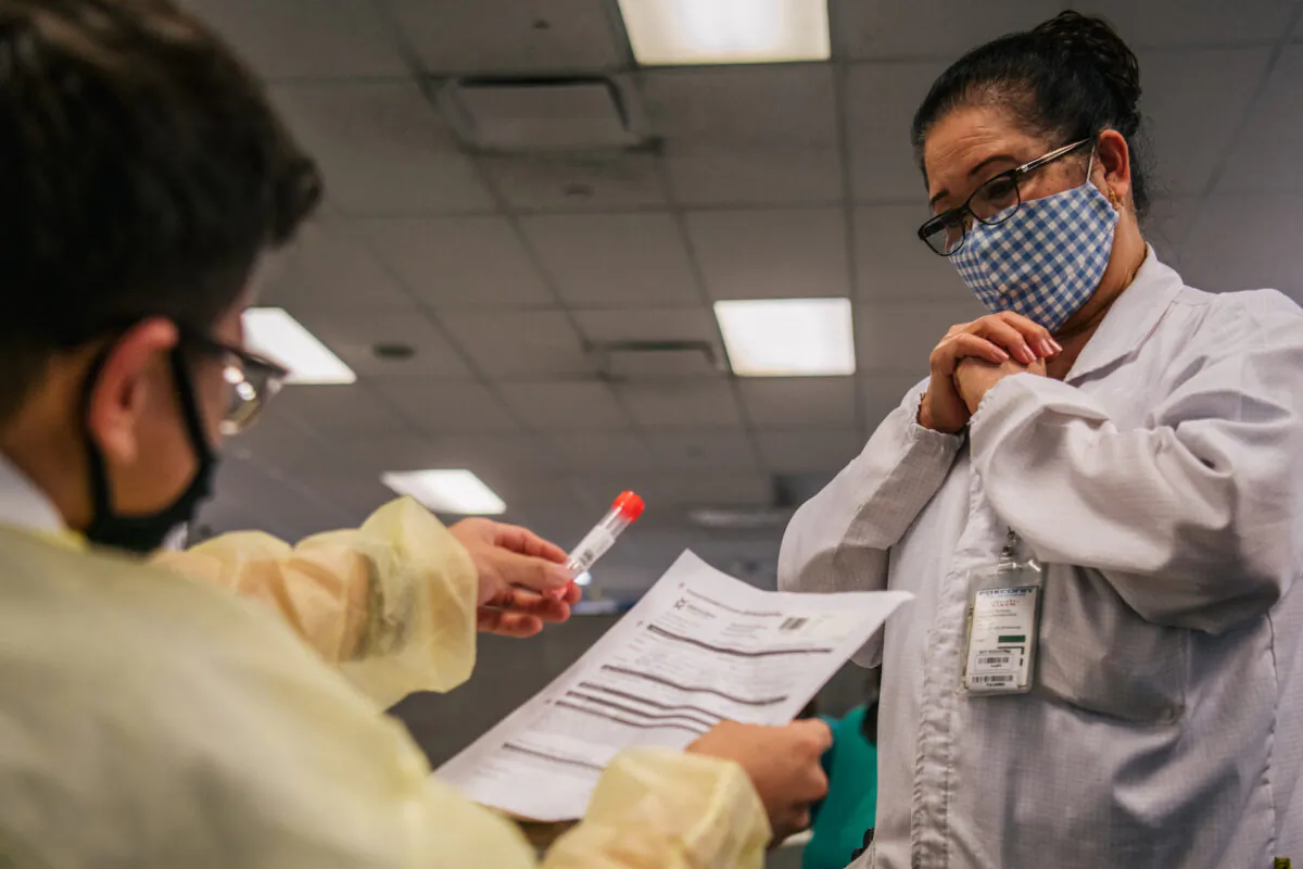 Genview Diagnosis medical assistant Kenny Tran gives a laboratory technician back her COVID-19 test-tube at Foxconn Assembly in Houston, Texas, on Aug. 13, 2021. (Brandon Bell/Getty Images)
