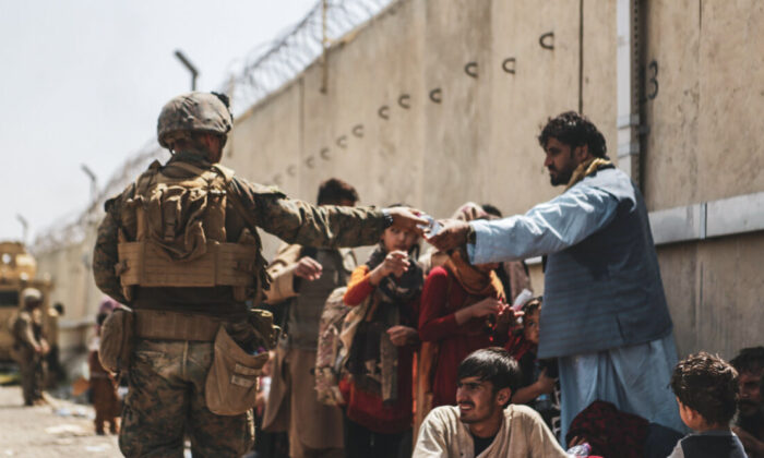 A Marine with the 24th Marine Expeditionary unit (MEU) passes out water to evacuees during the evacuation at Hamid Karzai International Airport during the evacuation in Kabul, Afghanistan, on Aug. 21, 2021. (Isaiah Campbell/U.S. Marine Corps via Getty Images)