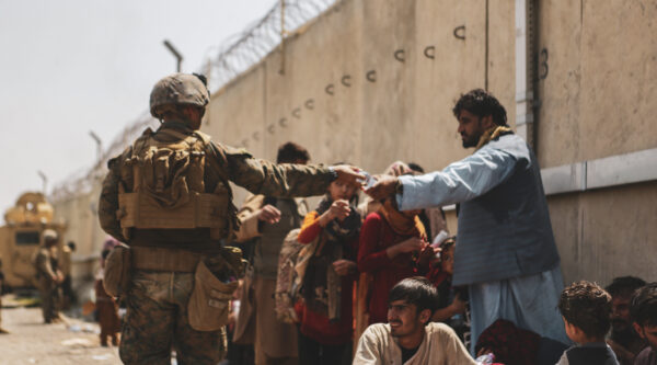 A Marine with the 24th Marine Expeditionary unit passes out water to evacuees during the evacuation at Hamid Karzai International Airport during the evacuation in Kabul, Afghanistan, on Aug. 21, 2021. (Isaiah Campbell/U.S. Marine Corps via Getty Images)