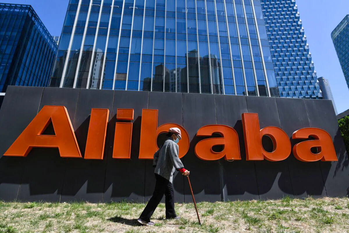 A woman walks past an Alibaba sign outside the company's office in Beijing, China, on April 13, 2021. (Greg Baker/AFP via Getty Images)