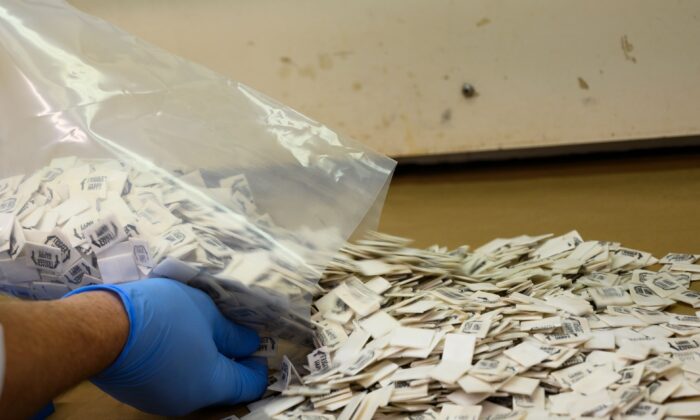 A Drug Enforcement Administration (DEA) chemist pours 2,500 packs of confirmed fentanyl onto a counter for testing at the DEA Northeast Regional Laboratory in New York on Oct. 8, 2019. (Don Emmert/AFP via Getty Images)