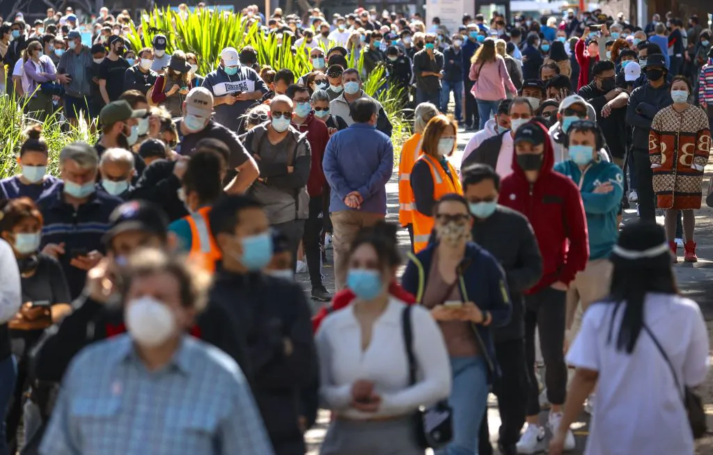 People wearing face masks stand in a line as they wait to be vaccinated at the Sydney Olympic Park Vaccination Centre at Homebush in Sydney, Australia, on Aug. 16, 2021. (David Gray/AFP via Getty Images)
