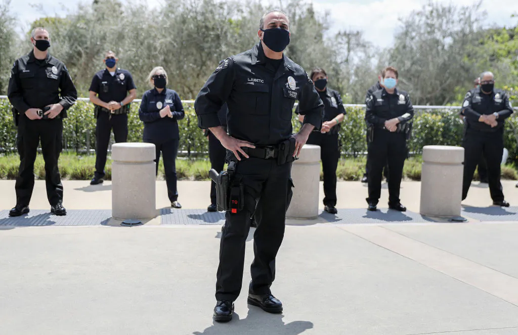 Los Angeles Police Department officers wear face masks as they wait to salute healthcare workers as a fellow LAPD detective is released
from Providence St. John's Health Center in Santa Monica, Calif., on April 17, 2020. (Mario Tama/Getty Images)
