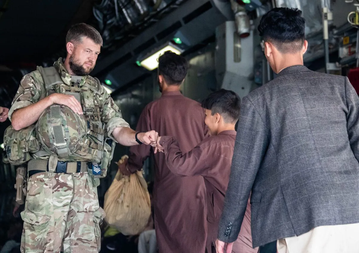 A member of the UK Armed Forces fist-bumping a child evacuee at Kabul airport in an undated file photo. (LPhot Ben Shread/MoD via PA)