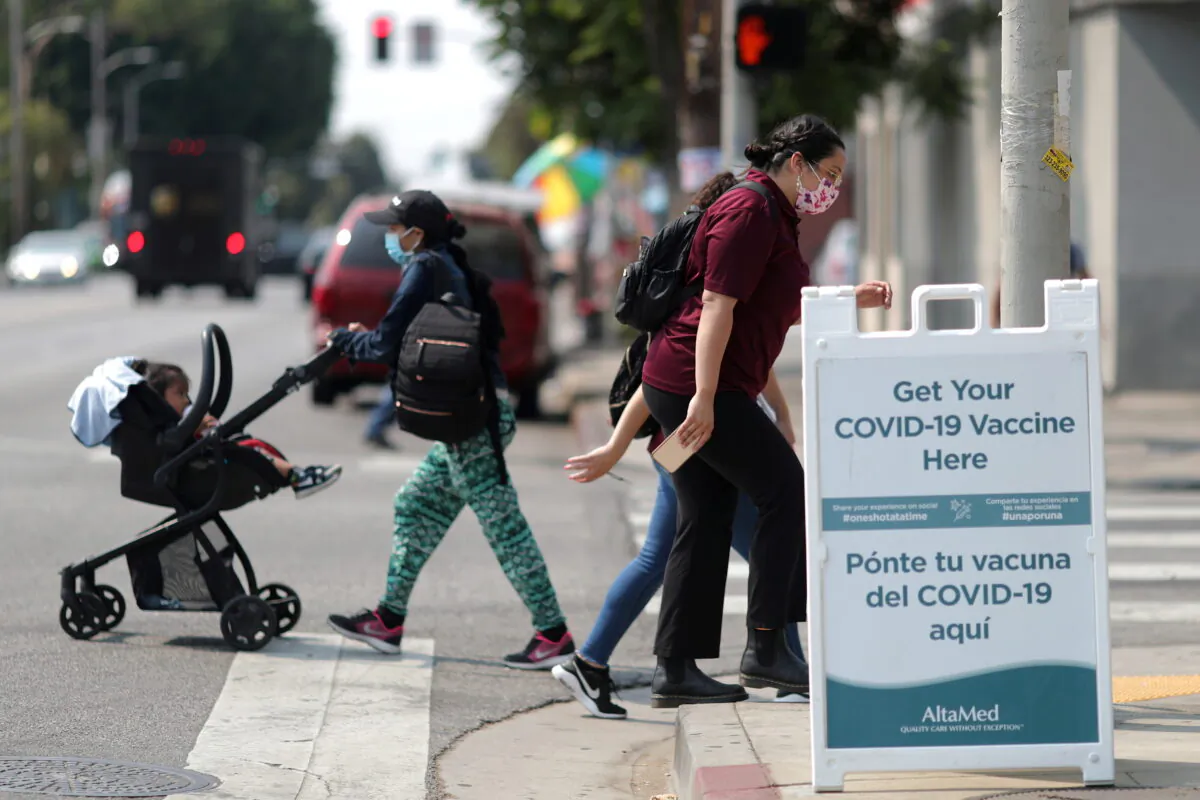 People walk past a sign for a COVID-19 vaccination clinic in Los Angeles, Calif., on Aug. 17, 2021. (Lucy Nicholson/Reuters)