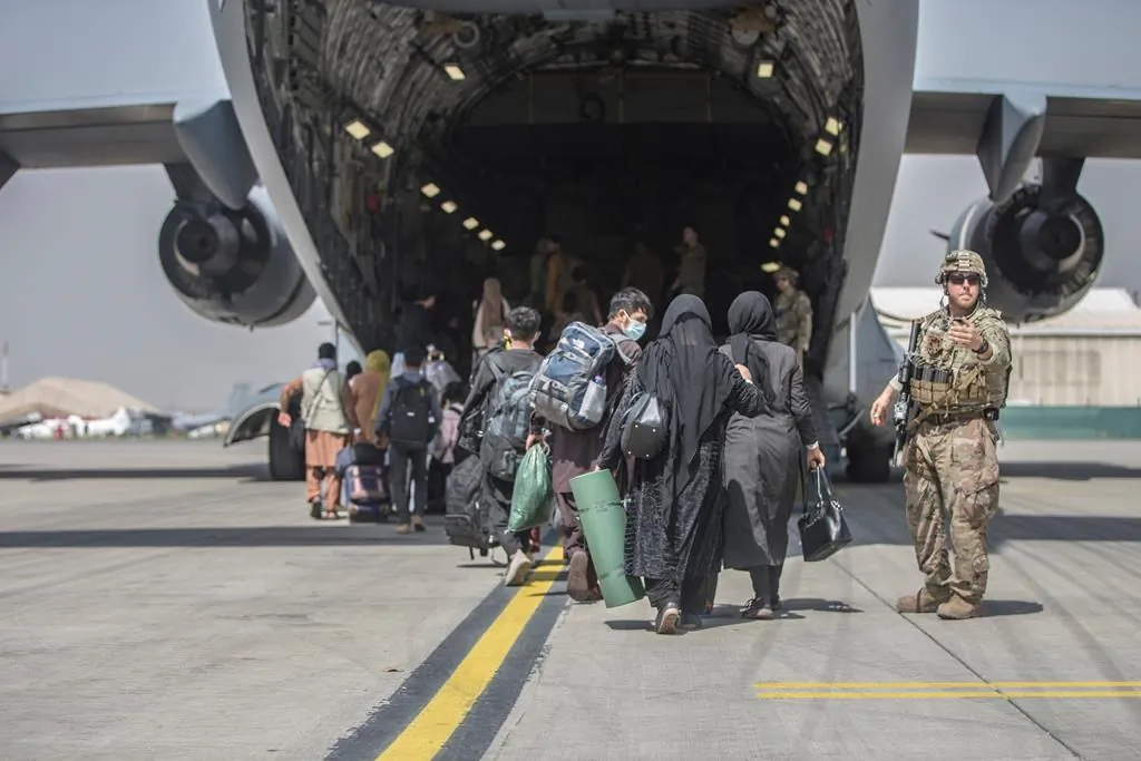 In this image provided by the U.S. Marine Corps, families begin to board a U.S. Air Force Boeing C-17 Globemaster III during an evacuation at Hamid Karzai International Airport in Kabul, Afghanistan, Aug. 23, 2021. (Sgt. Samuel Ruiz/U.S. Marine Corps via AP)