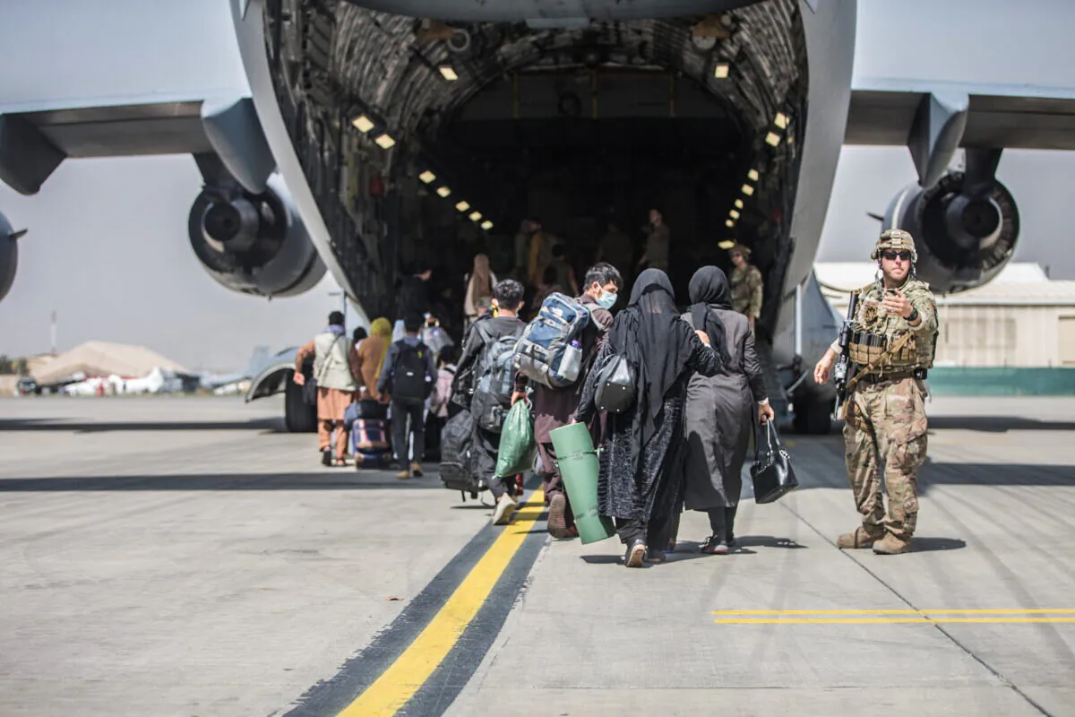 Families begin to board a U.S. Air Force C-17 Globemaster III transport plane during an evacuation at Hamid Karzai International Airport, Afghanistan, on Aug. 23, 2021. (U.S. Marine Corps/Sgt. Samuel Ruiz/Handout via Reuters)