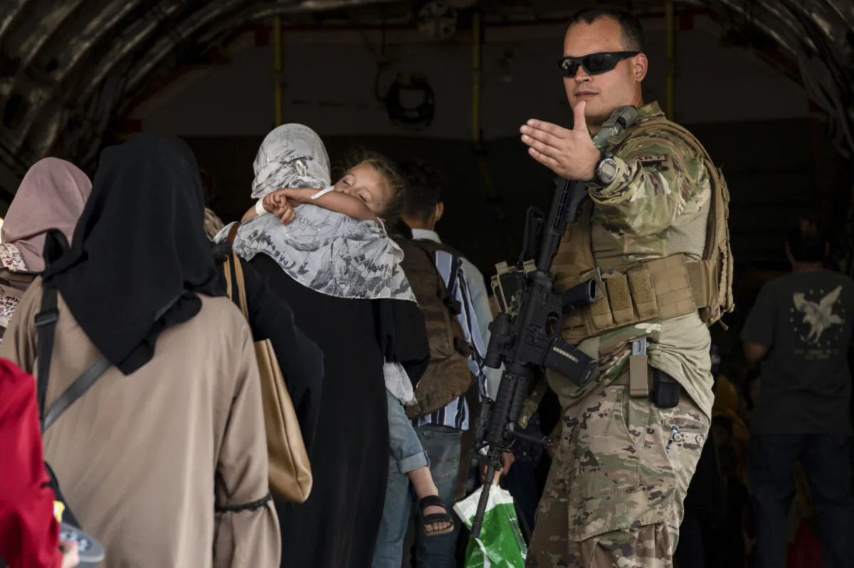 A U.S. Air Force Airman guides evacuees aboard a U.S. Air Force C-17 Globemaster III at Hamid Karzai International Airport in Kabul, Afghanistan, on Aug. 24, 2021. (Senior Airman Taylor Crul/U.S. Air Force via AP)