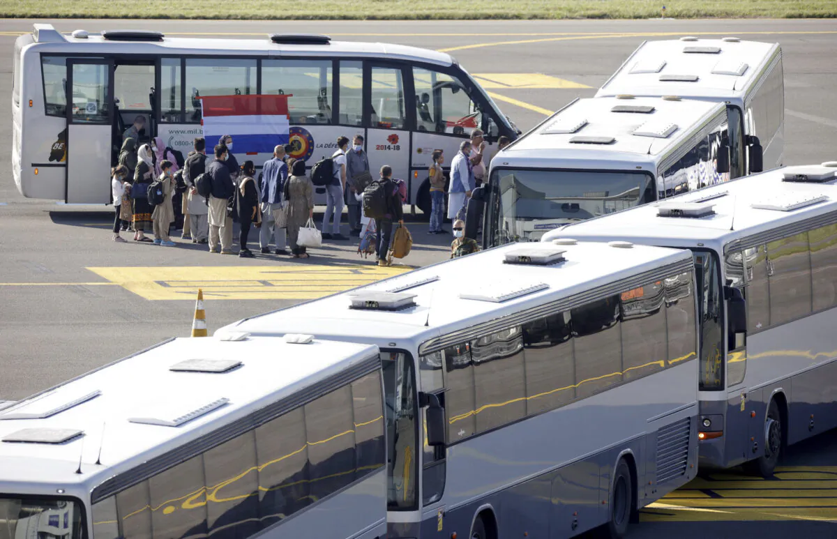 People disembark from a chartered plane and board waiting busses, after being evacuated from Afghanistan, during arrival at Melsbroek Military Airport in Melsbroek, Belgium, on Aug. 25, 2021. (Olivier Matthys/AP Photo)