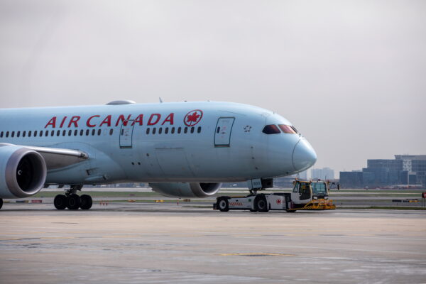 An Air Canada airplane is towed along a runway