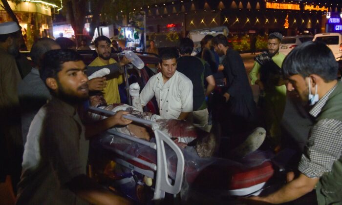 Volunteers and medical staff bring an injured man on a stretcher for treatment after explosions outside the airport in Kabul, Afghanistan, on Aug. 26, 2021. (Wakil Kohsar/AFP via Getty Images)