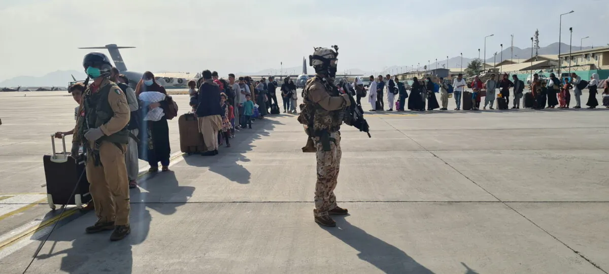 Afghan evacuees queue before boarding Italy's military aircraft C130J during evacuation at Kabul airport, Afghanistan on Aug. 22, 2021. (Italian Ministry of Defence/Handout via Reuters)