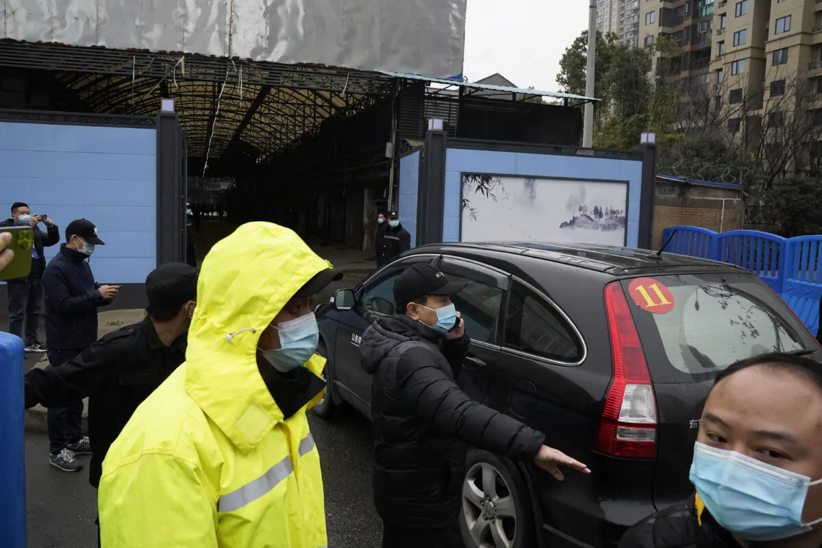 Security personnel clear the way for a convoy of the World Health Organization team to enter the Huanan Seafood Market on the third day of field visit in Wuhan in central China's Hubei province, on Jan. 31, 2021. (Ng Han Guan/AP Photo)