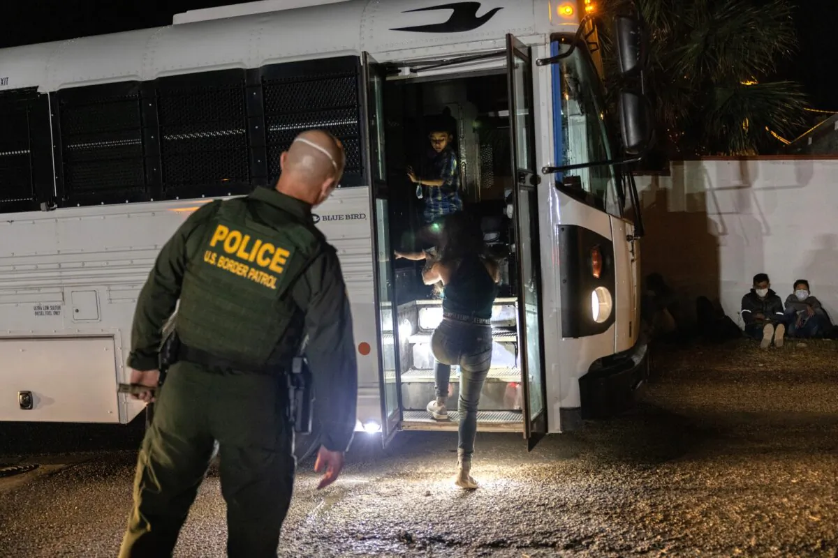 A U.S. Border Patrol agent supervises as immigrants board a bus to a processing center in Roma, Texas on Aug. 14, 2021. (John Moore/Getty Images)