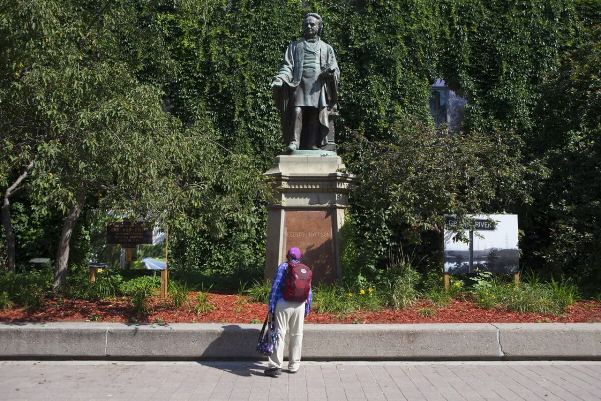 A passer-by looks at a statue of Egerton Ryerson outside Toronto's Ryerson University on July 6, 2017. The statue has since been toppled and will not be replaced, and Ryerson’s board of governors has now approved a name change for the university. (The Canadian Press/Chris Young)