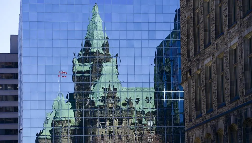 The Confederation Building reflects off the windows of a building in downtown Ottawa in a file photo. (The Canadian Press/Sean Kilpatrick)