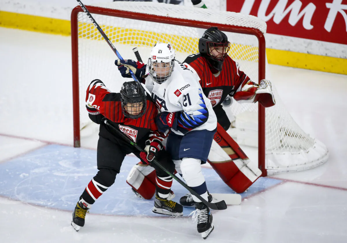 Hilary Knight, centrer, of the United States, tries to hold her position as Japan's Shiori Koike checks in front of Japan goalie Nana Fujimoto during second-period quarterfinal IIHF women's world championship hockey game action in Calgary, Alberta, on Aug. 28, 2021. (Jeff McIntosh/The Canadian Press via AP)