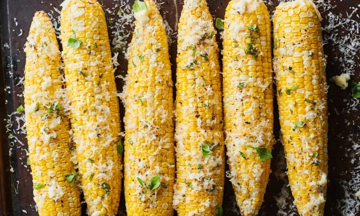 Sweet, slightly charred roasted corn is rubbed with Parmesan-garlic butter and showered with more Parmesan and fresh basil. (Joe Lingeman/TNS)