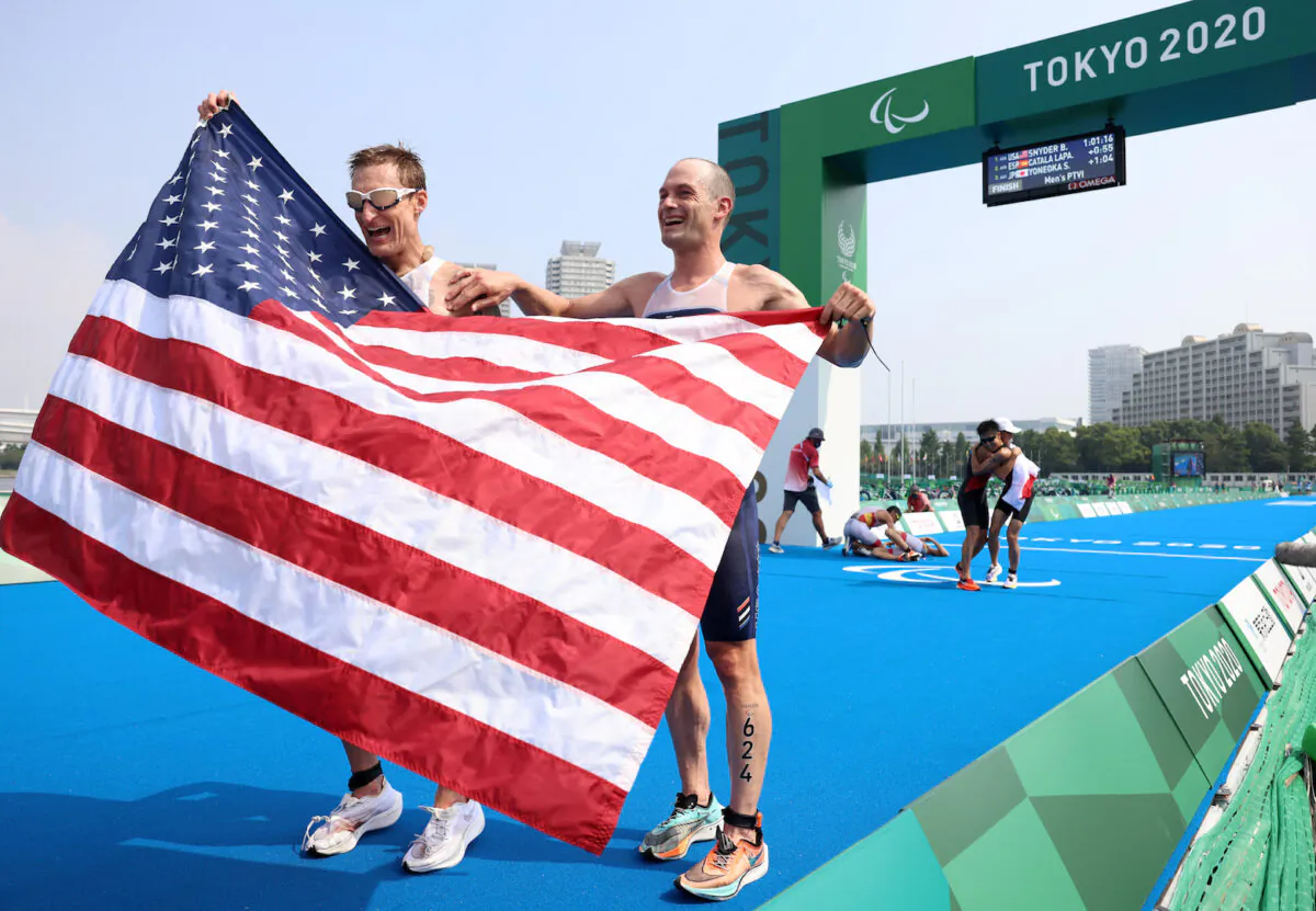 Brad Snyder and guide Greg Billington of Team United States react as they cross the finish line to win the gold medal during the men's PTVI Triathlon on day 4 of the Tokyo 2020 Paralympic Games at Odaiba Marine Park on Aug. 28, 2021 in Tokyo, Japan. (Lintao Zhang/Getty Images)