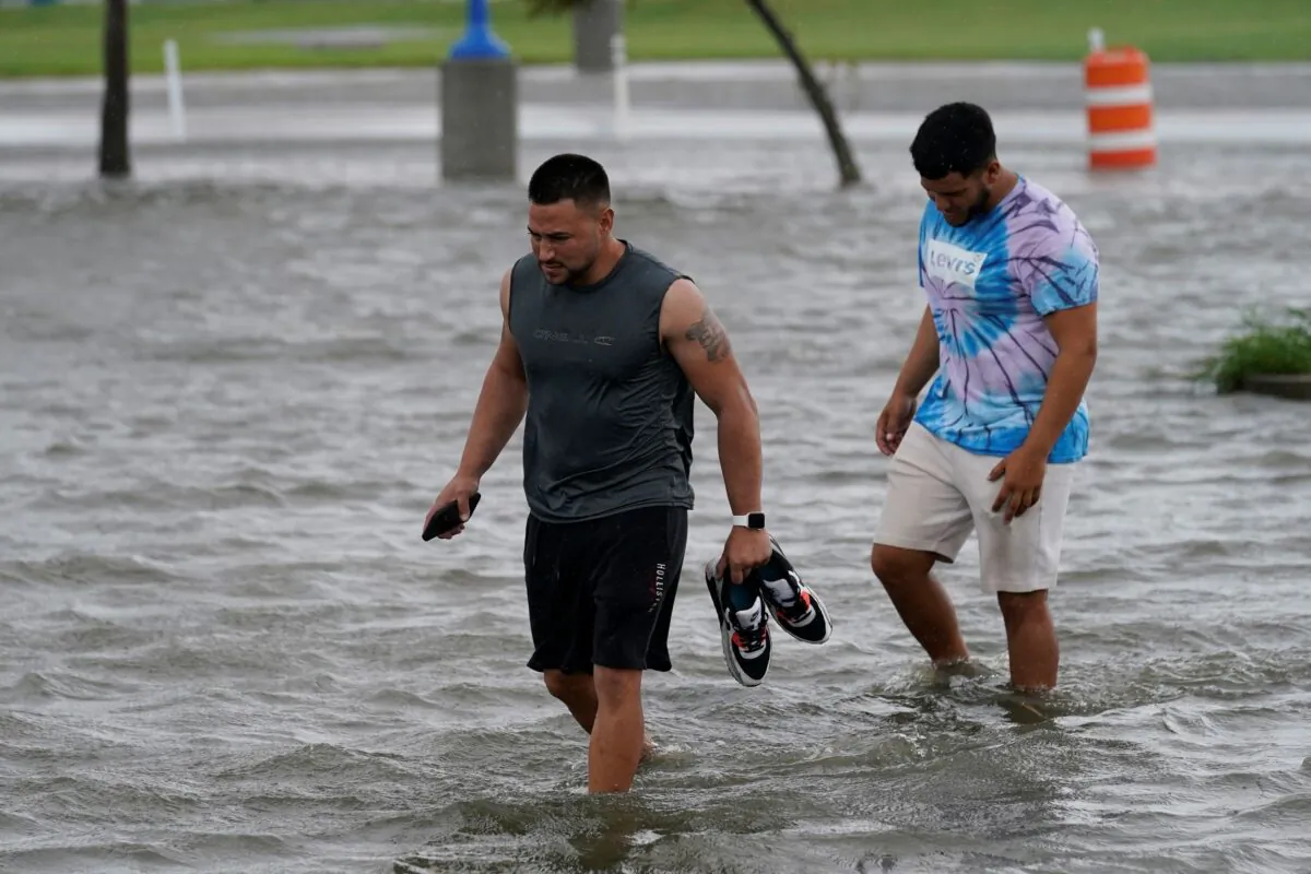 People walk through flooded streets near Lake Pontchartrain as Hurricane Ida nears, in New Orleans, La., on Aug. 29, 2021. (Gerald Herbert/AP Photo)