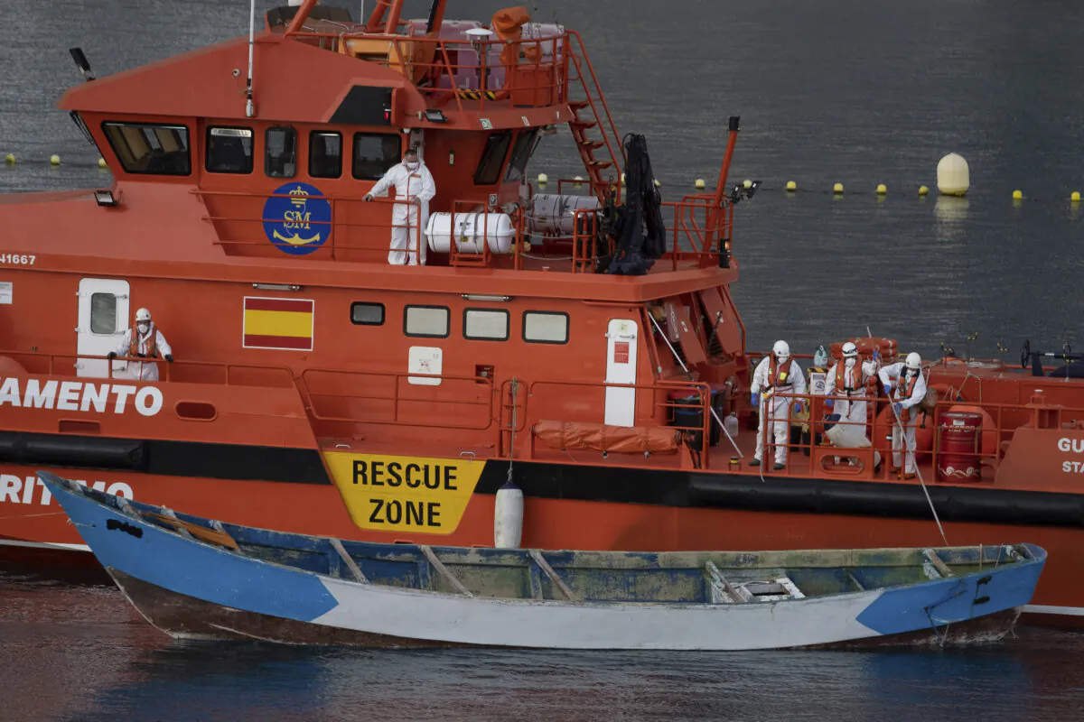 A wooden boat is towed by a Spanish Maritime Rescue Service ship as they arrive at the port of Los Cristianos in the south of Tenerife, in the Canary Island, Spain, on April 28, 2021. (Andres Gutierrez/AP Photo)