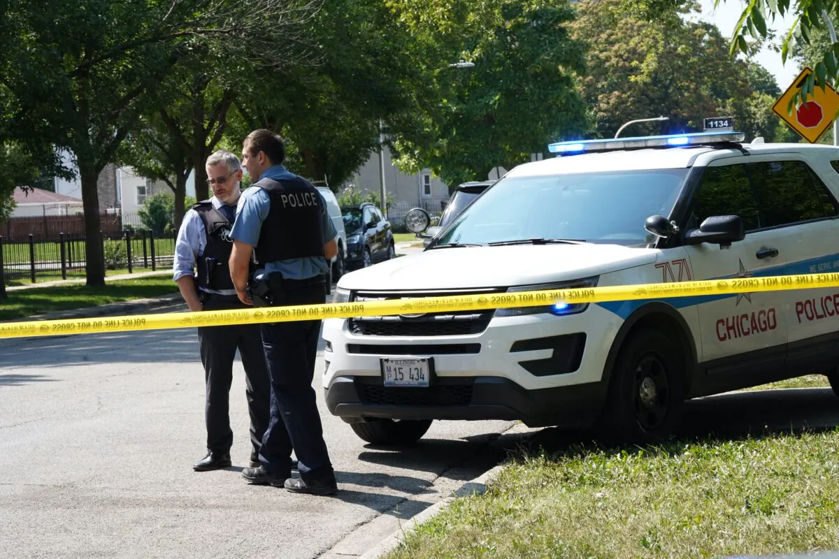 A Chicago police officer talks with a detective at 3443 W. Monroe St. where three people were shot half an hour earlier on Aug. 20, 2021. (Cara Ding/The Epoch Times)