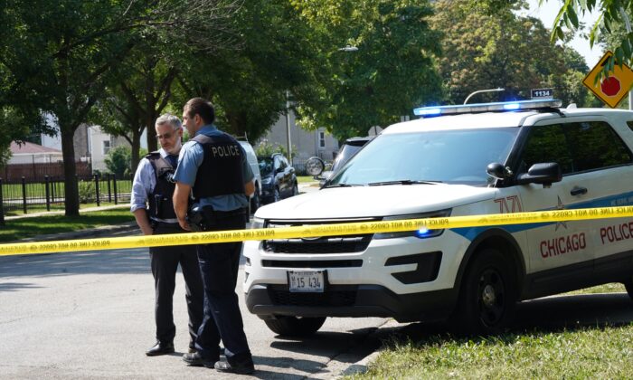 A Chicago police officer talks with a detective at 3443 W. Monroe Street where three people were shot half an hour earlier on Aug. 20, 2021. (Cara Ding/  Pezou)