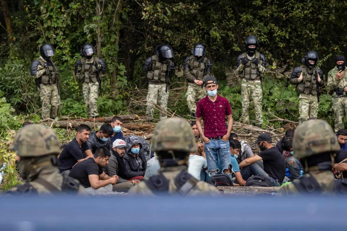A member of a group of migrants believed to be from Afghanistan stands as he tries to confirm their will to apply for international protection in Poland to Polish volunteer lawyers, in the presence of press members and Polish Parliament deputies, in the small village of Usnarz Gorny near Bialystok, northeastern Poland, located close to the border with Belarus, on Aug. 20, 2021. (Wojtek Radwanski/AFP via Getty Images)