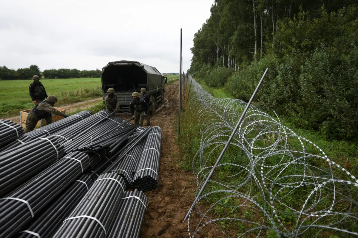 Polish soldiers unload materials to construct a barbed wire fence on the border with Belarus in Zubrzyca Wielka near Bialystok, eastern Poland, on Aug. 26, 2021. (Jaap Arriens/AFP via Getty Images)