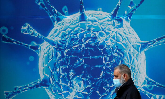 A man passing an illustration of a virus outside the Regional Science Center in Oldham, England, on August 3, 2020.  (Phil Noble / Reuters)