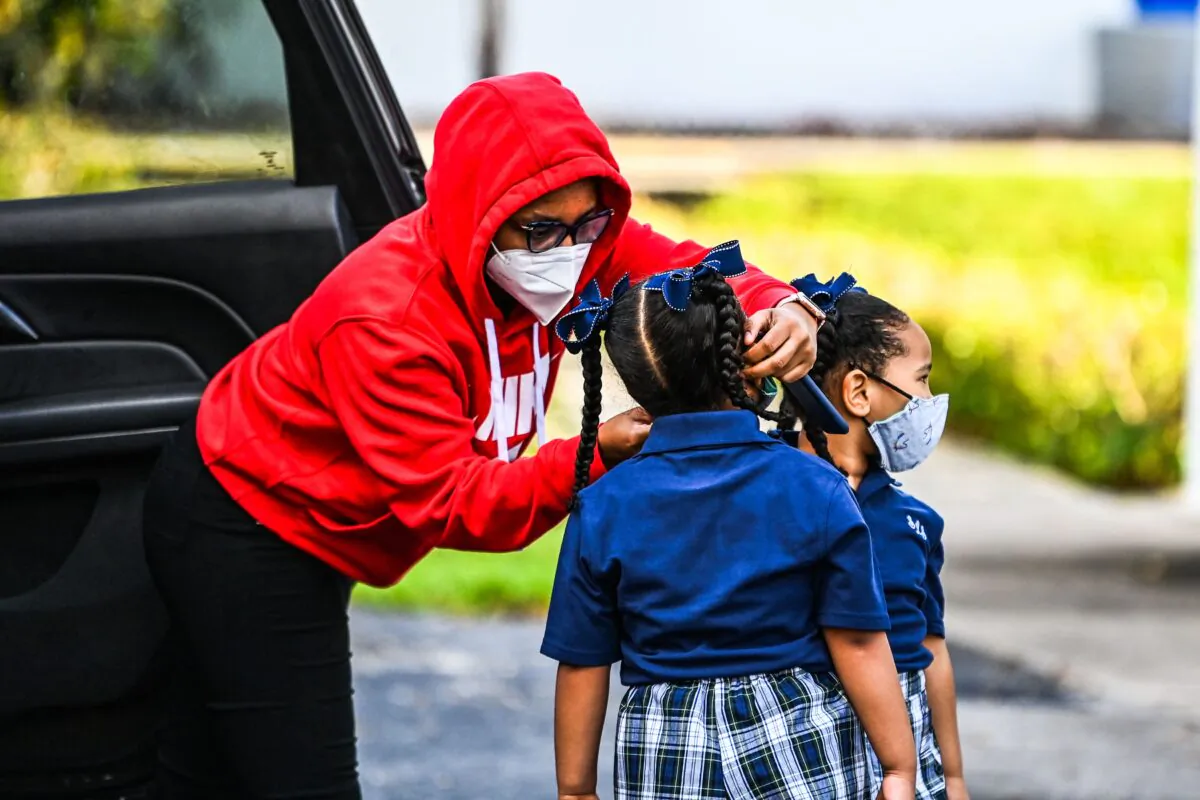 A mother adjusts the facemask of her child as she enters the St. Lawrence Catholic School on the first day of school after summer vacation in north of Miami on Aug. 18, 2021. (Chandan Khanna/AFP via Getty Images)
