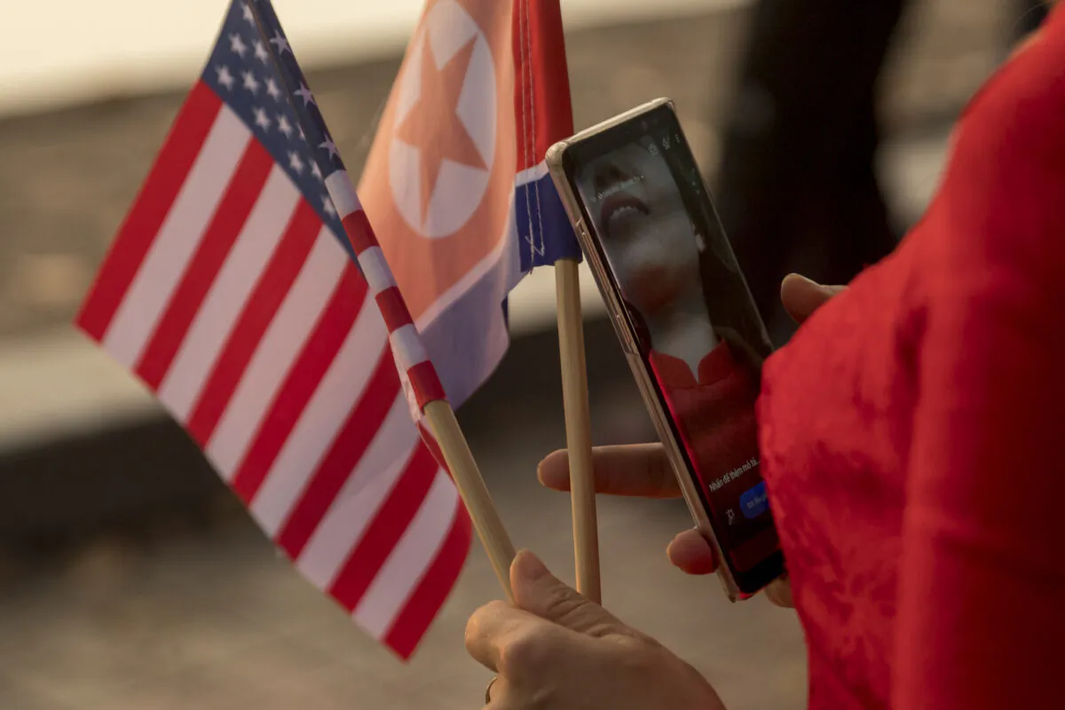 A woman holds American and North Korean flags as she walks along Sword Lake in Hanoi, Vietnam, on Feb. 27, 2019. (Andrew Harnik/AP Photo)