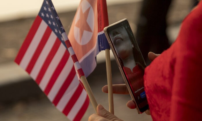 A woman holds American and North Korean flags as she walks along Sword Lake in Hanoi, Vietnam, on Feb. 27, 2019. (Andrew Harnik/AP Photo)