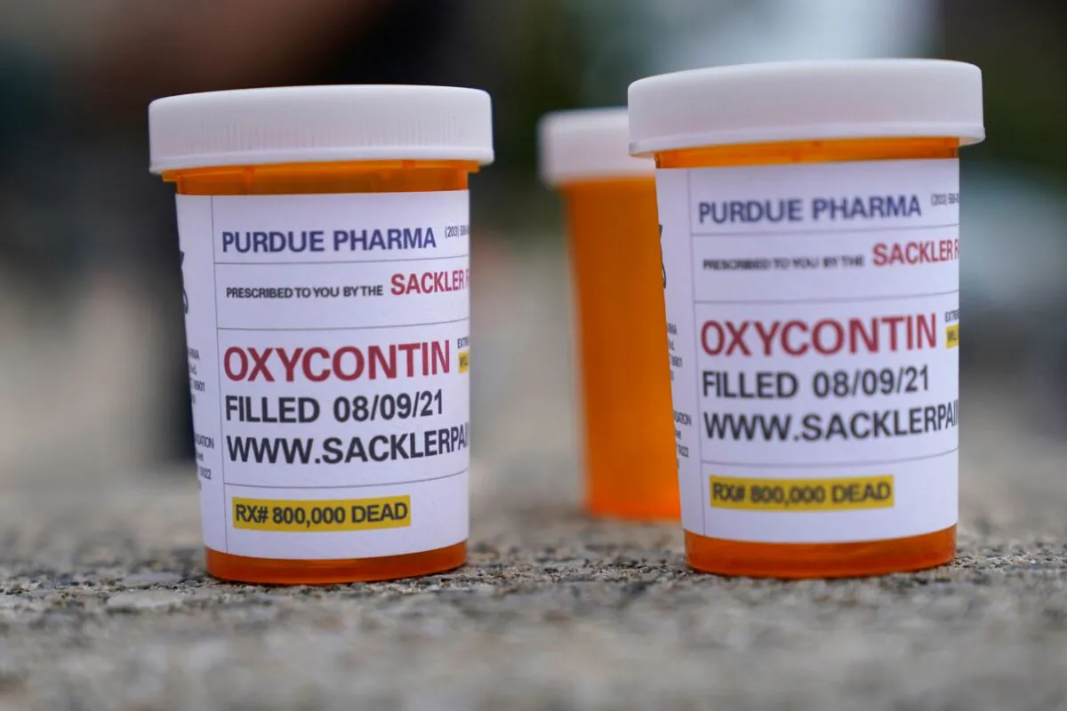 Fake pill bottles with messages about OxyContin maker Purdue Pharma are displayed during a protest outside the courthouse where the bankruptcy of the company is taking place in White Plains, N.Y., on Aug. 9, 2021. (Seth Wenig/File/AP Photo)